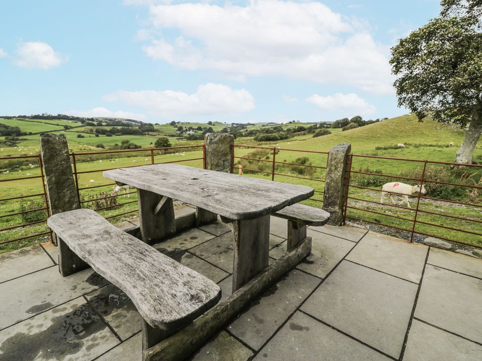 An outdoor area with a stone table and benches at Orsedd Wen Farmhouse in Betws-Y-Coed
