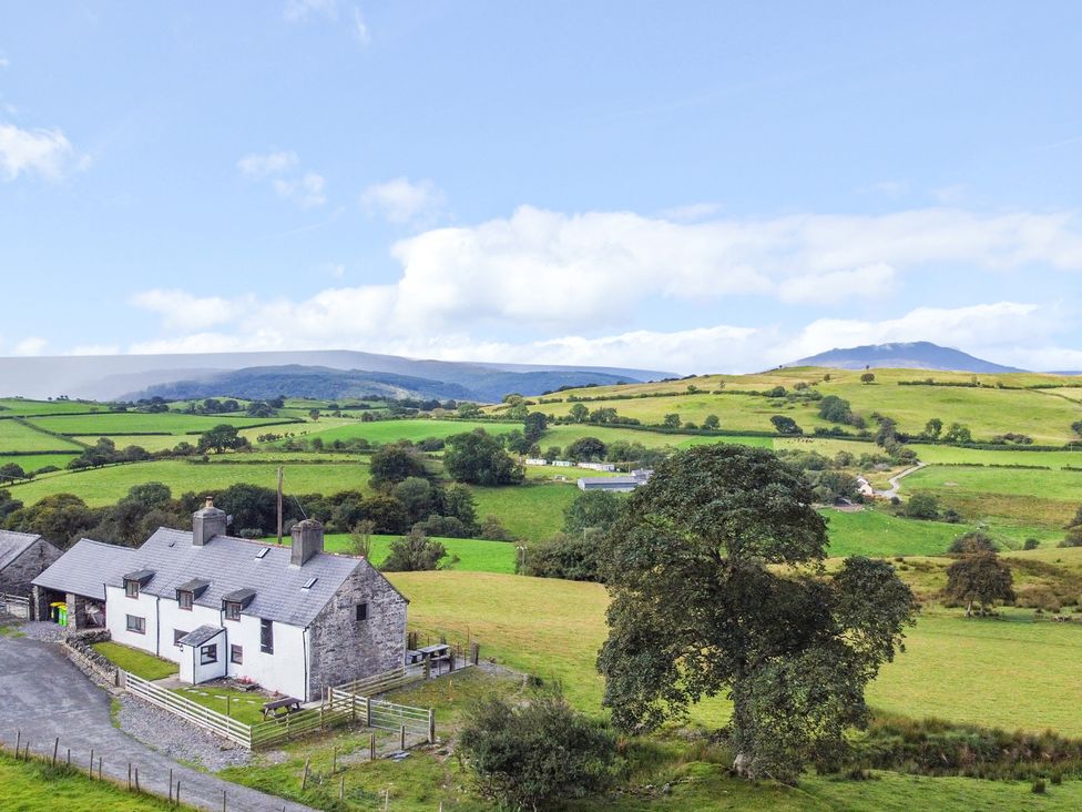 A house in a field with mountains in the background at Orsedd Wen Farmhouse Betws-Y-Coed