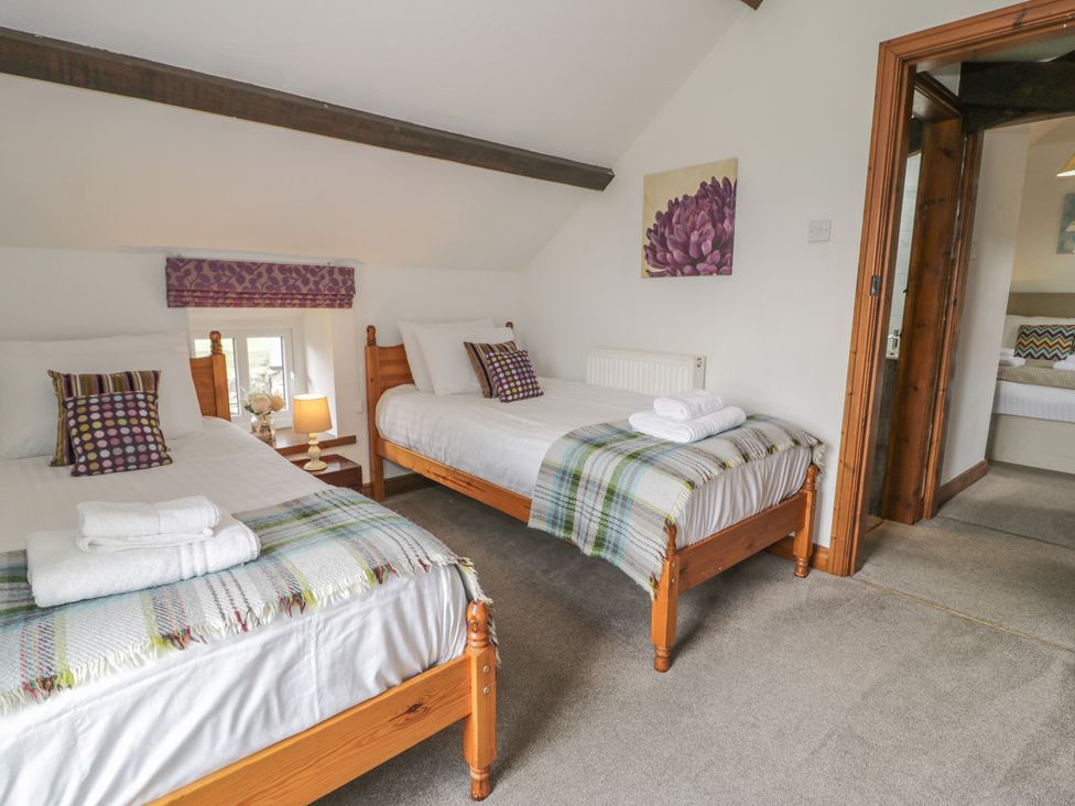 A bedroom with two beds and a lamp at Orsedd Wen Cottage in Betws-Y-Coed