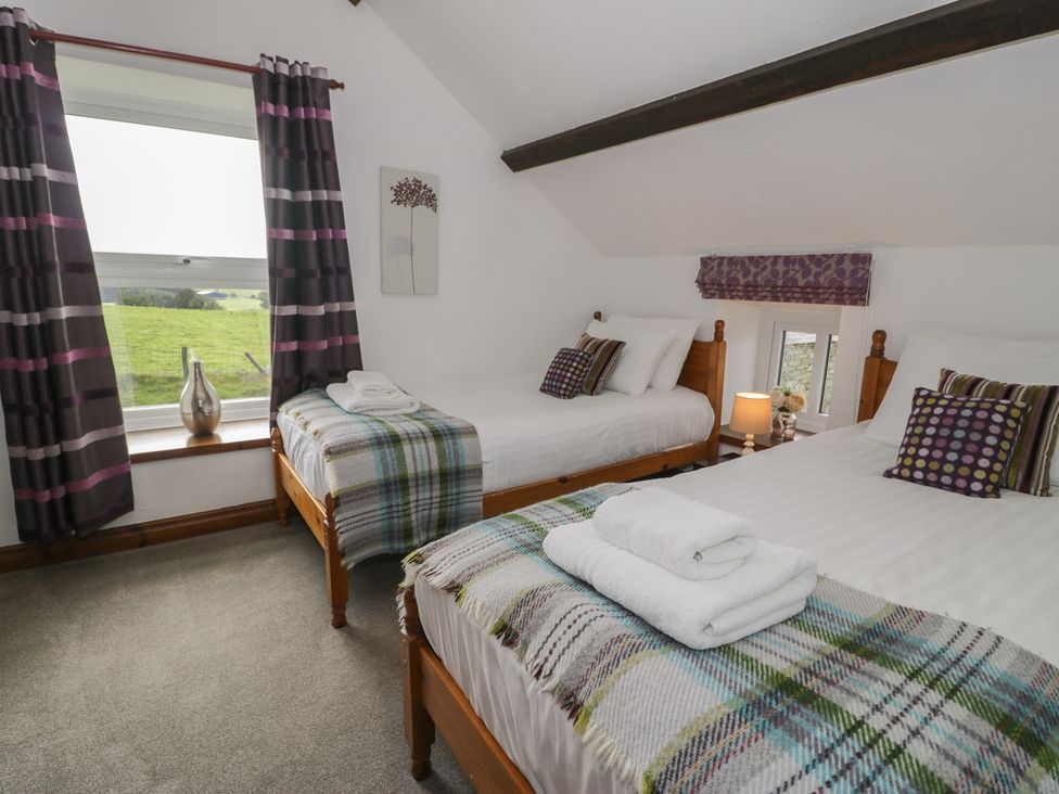 A bedroom with two beds and a window at Orsedd Wen Cottage Betws-Y-Coed