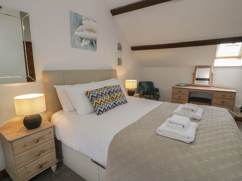 A bedroom with a bed and lamp at Orsedd Wen Cottage in Betws-Y-Coed