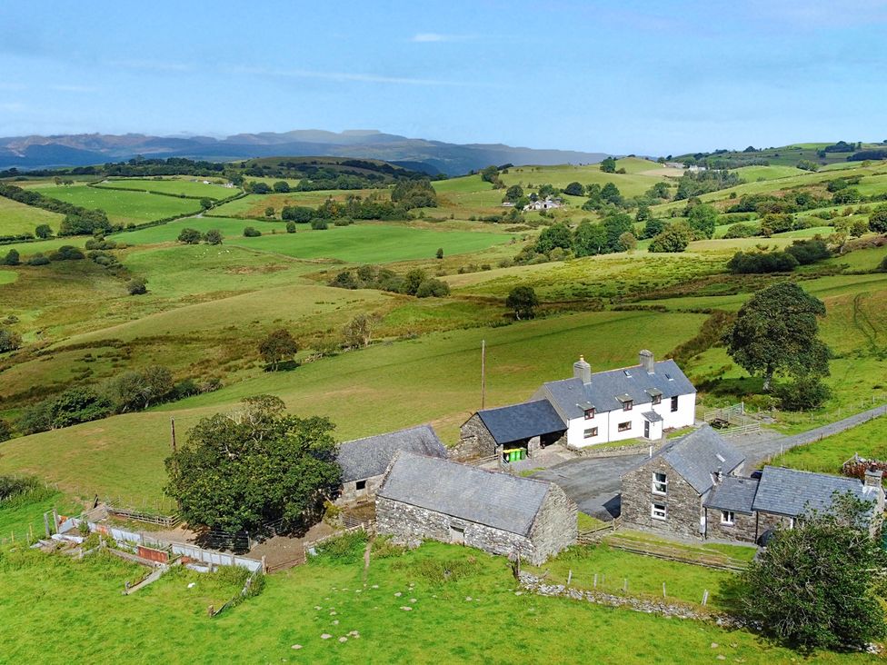 An aerial view of a house and farm buildings surrounded by fields at Orsedd Wen Cottage in Betws-Y-Coed