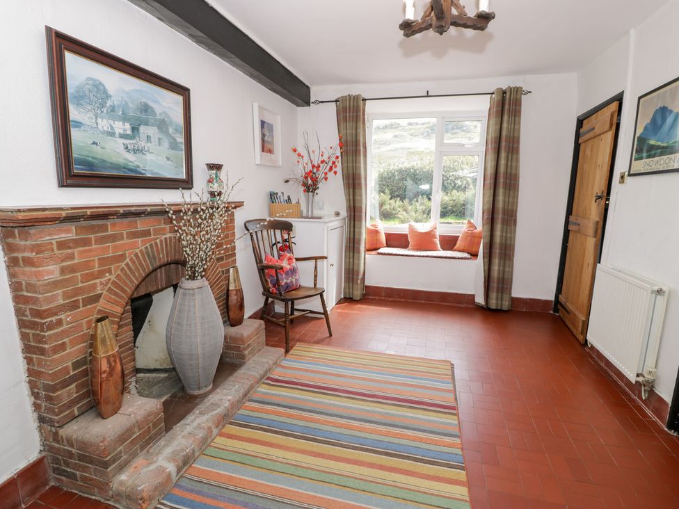 A living room with a fireplace and chair at Cwm in Capel Curig