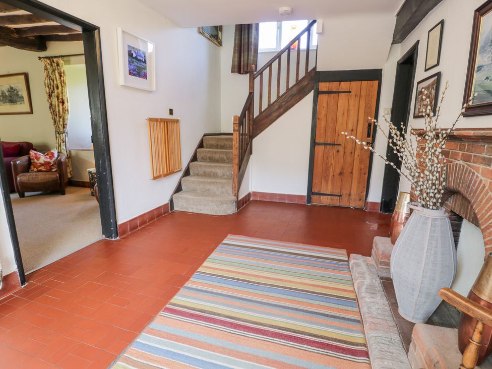 A hallway with a staircase, a door, and a rug at Cwm in Capel Curig