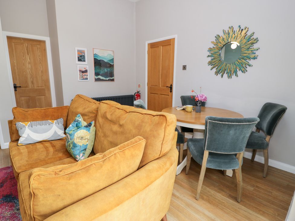 A living room with a yellow sofa and a round table at Pengwern Bach in Llanrwst