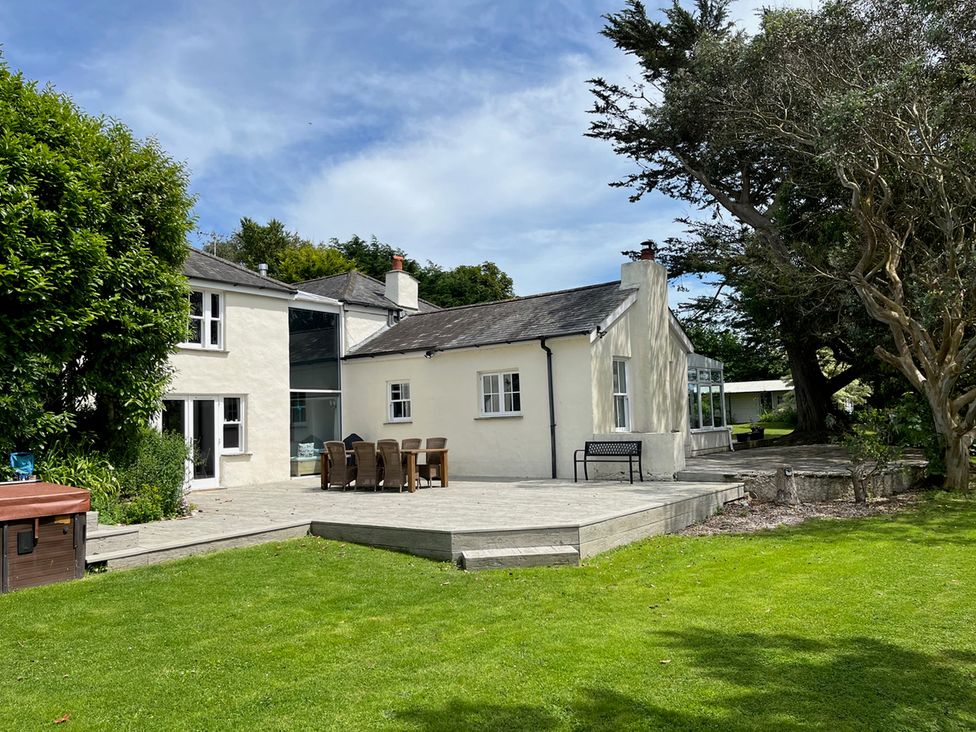 An outdoor area with a house, deck, chairs and a hot tub at Otterburn House in Bude