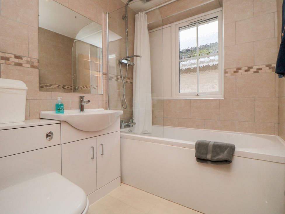 A bathroom with a bathtub, sink, toilet and a window at 17 Costa Way in Pickering