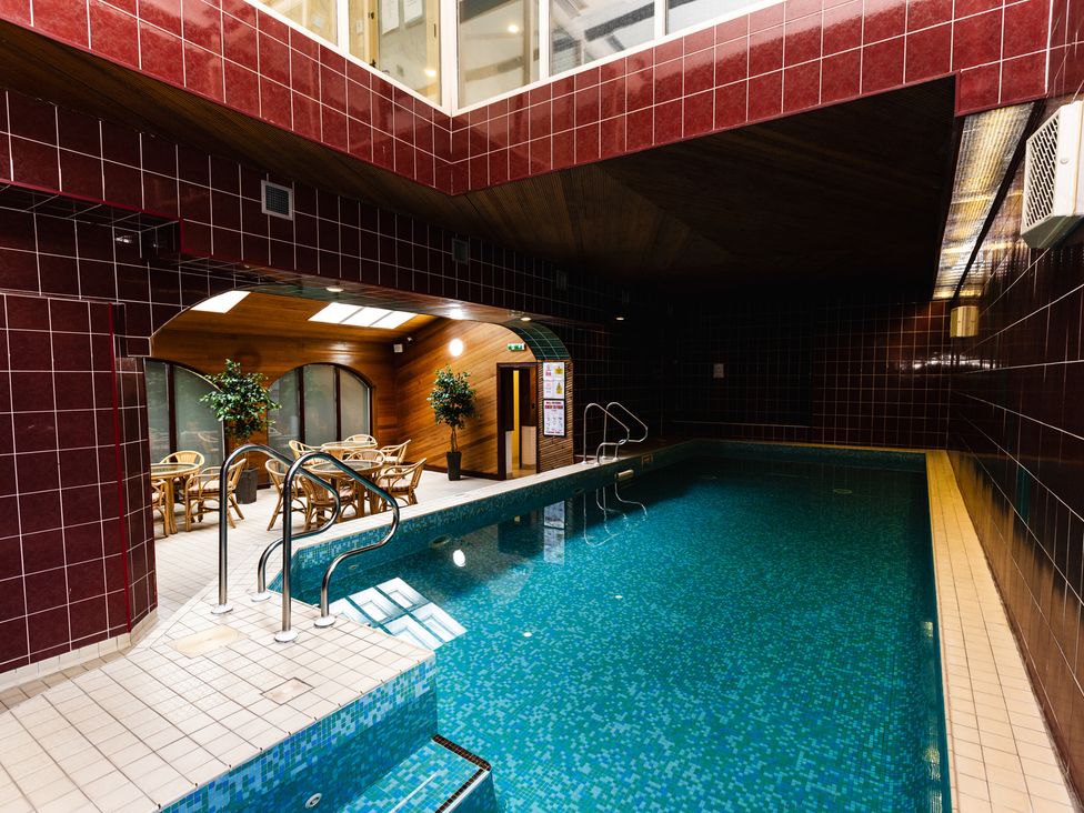 An indoor pool area with seating and plants at Rose Cottage in Akeld near Wooler