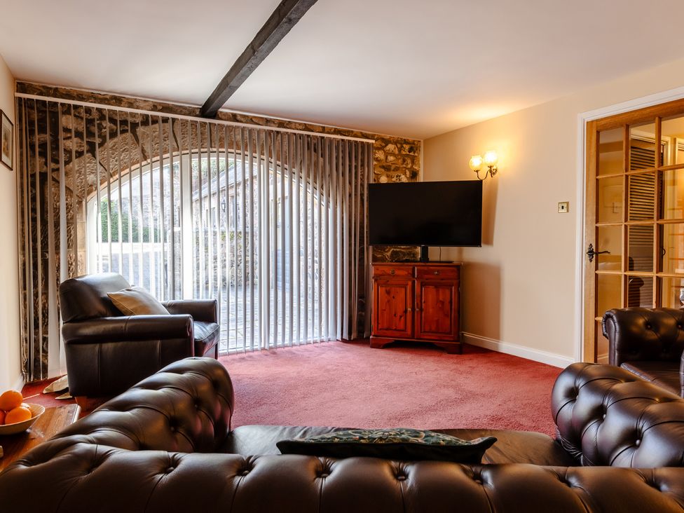 A living room with a sofa and television at Fern Cottage in Akeld near Wooler