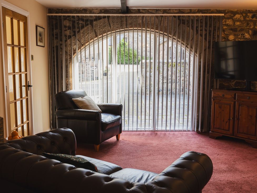A living room with an armchair, sofa, and television at Fern Cottage Akeld near Wooler