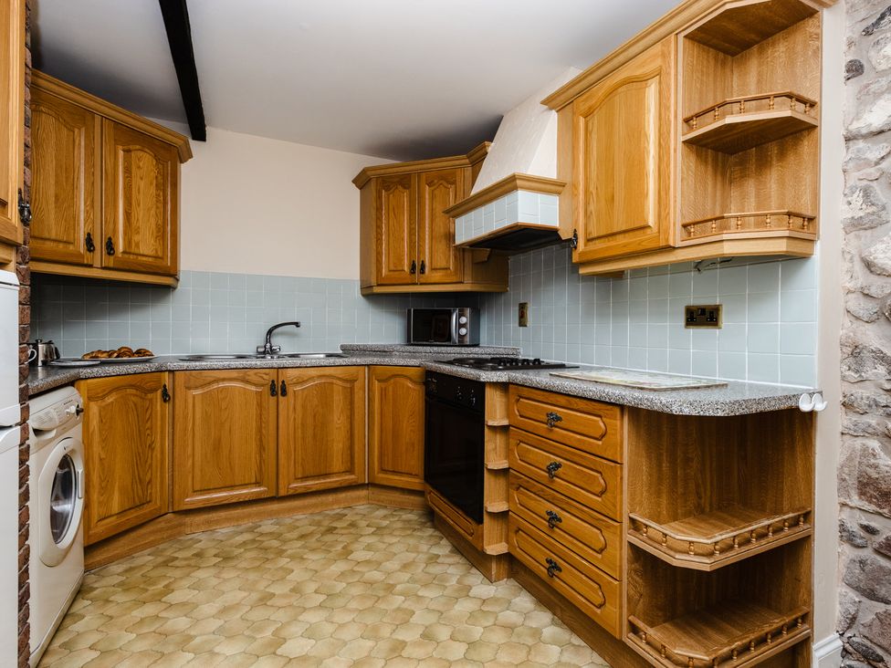 A kitchen with wooden cabinets and appliances at Fern Cottage Akeld near Wooler