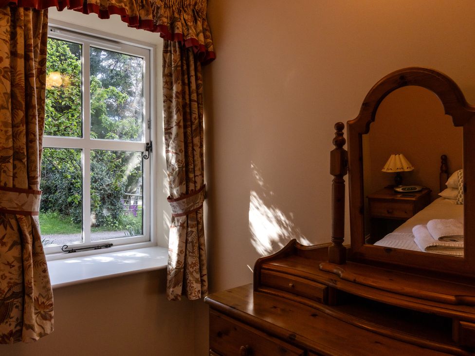 A bedroom with a window and dressing table at Fern Cottage in Akeld near Wooler