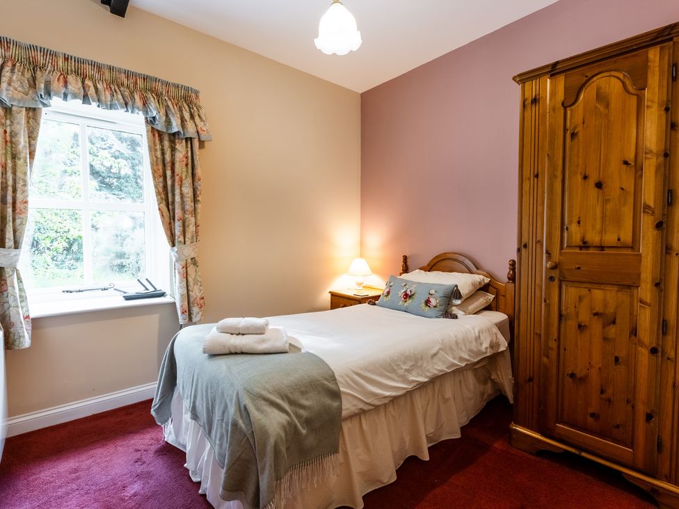 A bedroom with a bed and wardrobe at Fern Cottage near Wooler
