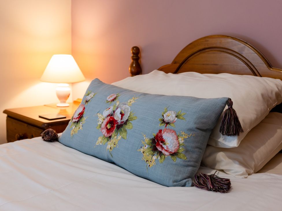 A bed with a decorative pillow and lamp at Fern Cottage Akeld near Wooler