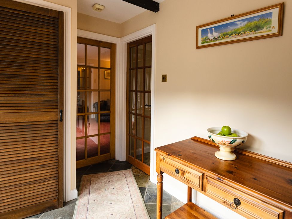 A hallway with an entrance table and green apples in a bowl at Fern Cottage Akeld near Wooler