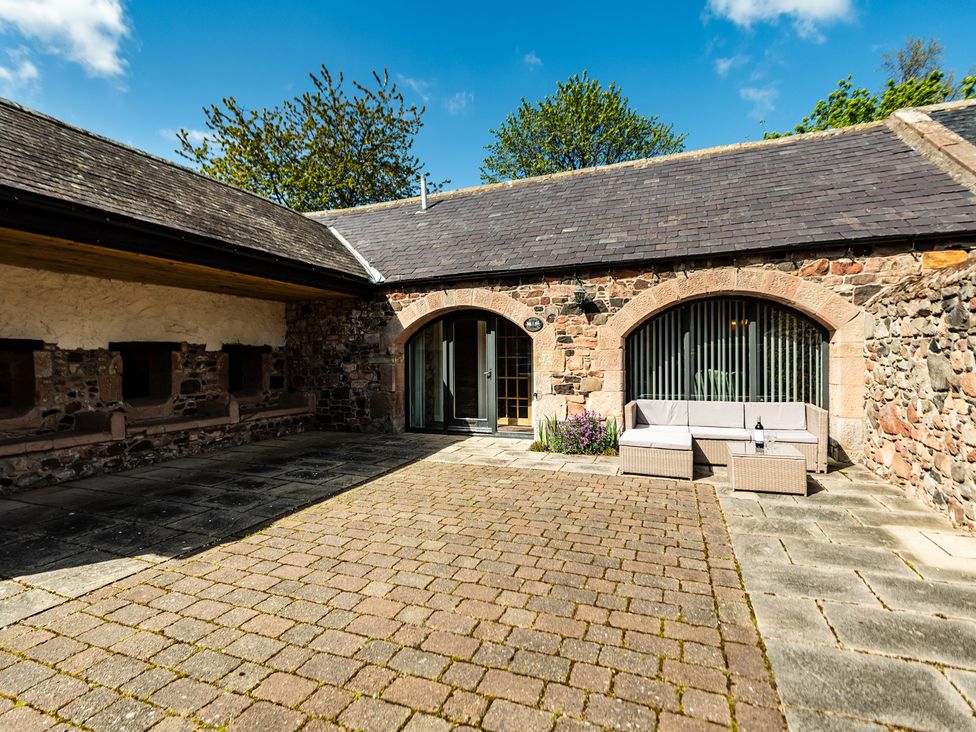 An outdoor seating area with stone walls and paved surface at Lupin Cottage near Wooler