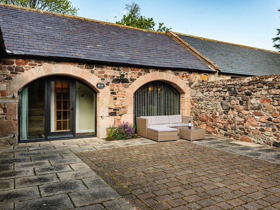 An outdoor seating area with a couch and coffee table at Lupin Cottage in Akeld near Wooler