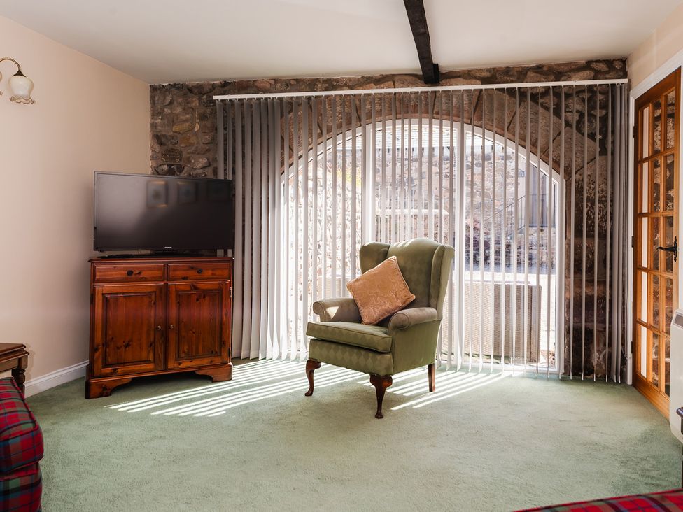 A living room with a television and an armchair at Lupin Cottage near Wooler