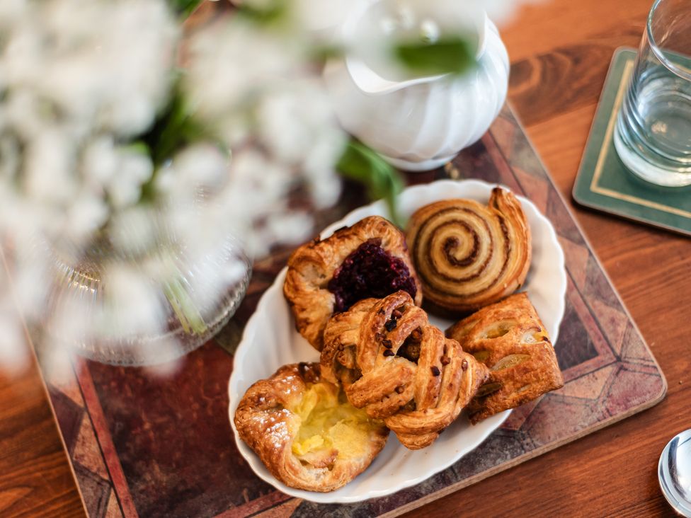 A plate of pastries with a coffee pot and flowers at Lupin Cottage in Akeld near Wooler