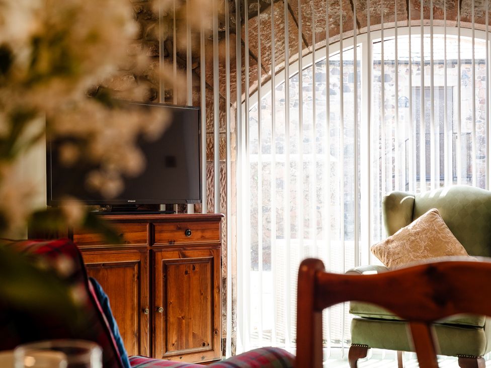 A living room with a television and a wooden cabinet at Lupin Cottage Akeld near Wooler