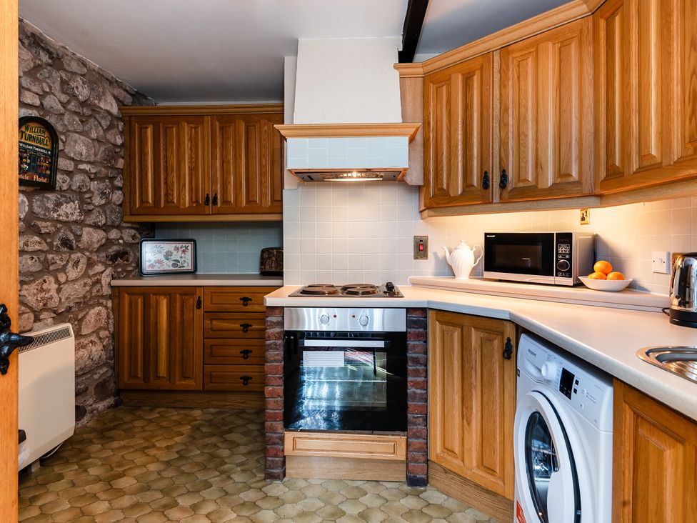 A kitchen with wooden cabinets and appliances at Lupin Cottage in Akeld near Wooler
