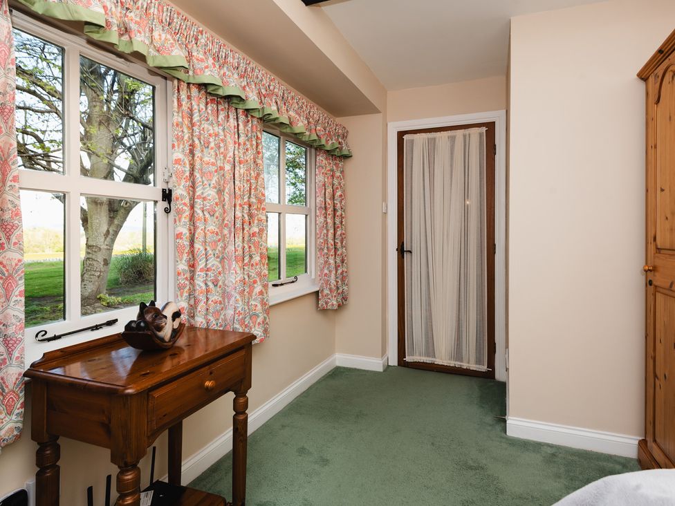 A bedroom with windows and green carpet at Lupin Cottage in Akeld near Wooler