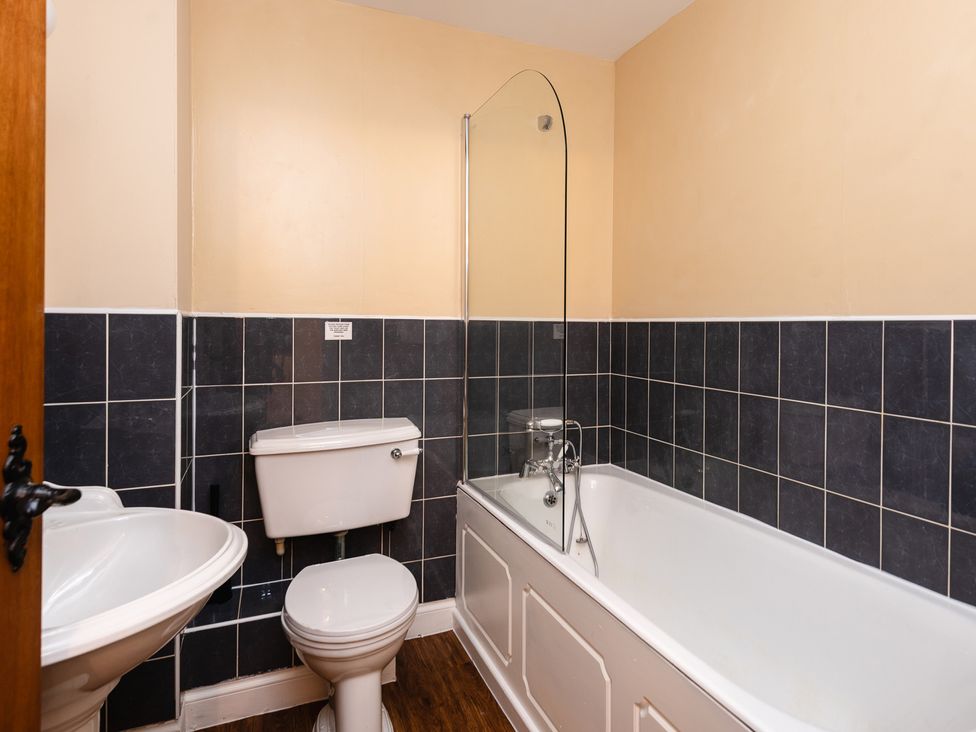 A bathroom with a toilet, bathtub, and sink at Lupin Cottage Akeld near Wooler