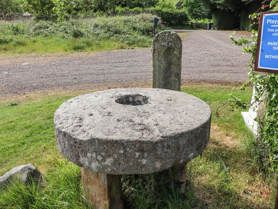 A stone millstone beside a gravel road at Cherryburn Cottage Akeld near Wooler