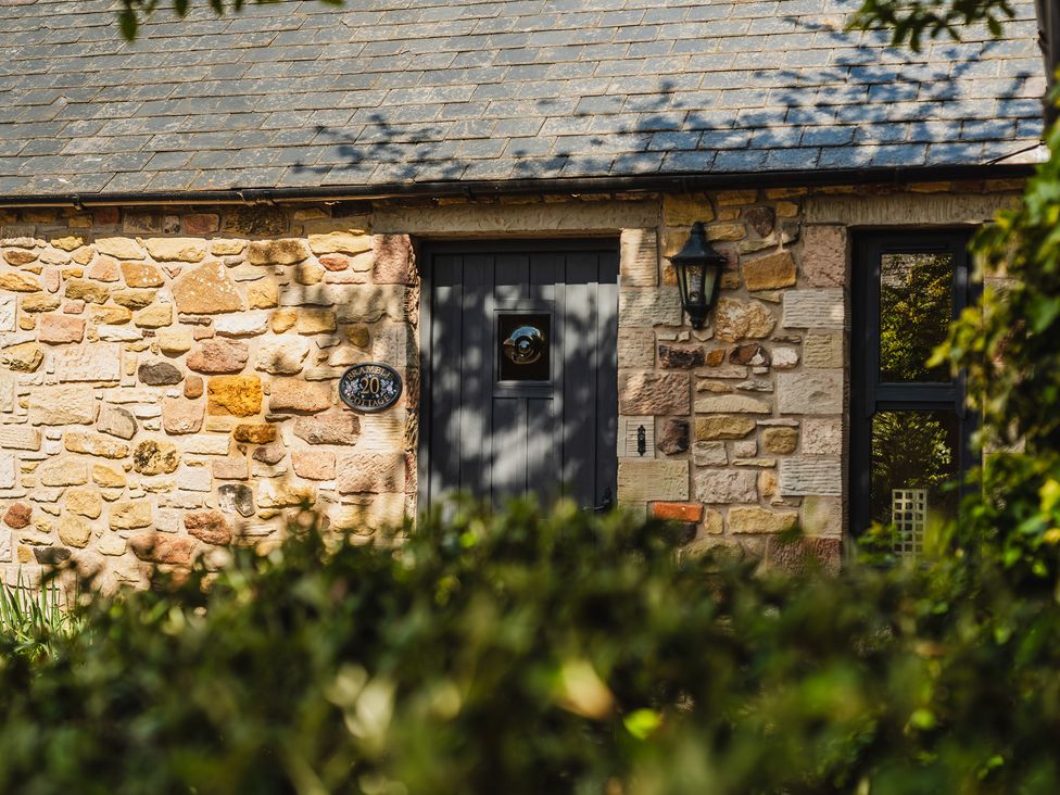 A stone wall with a door and window at Bramble Cottage in Akeld near Wooler