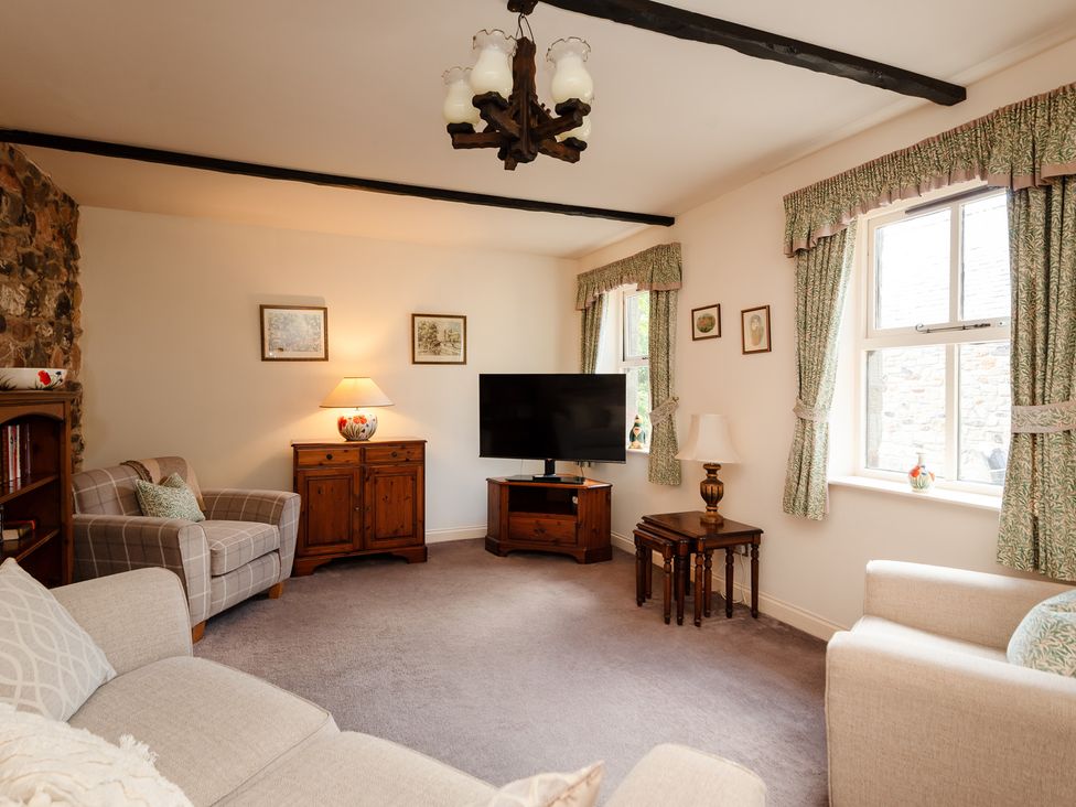 A living room with sofa and television at Bramble Cottage in Akeld near Wooler