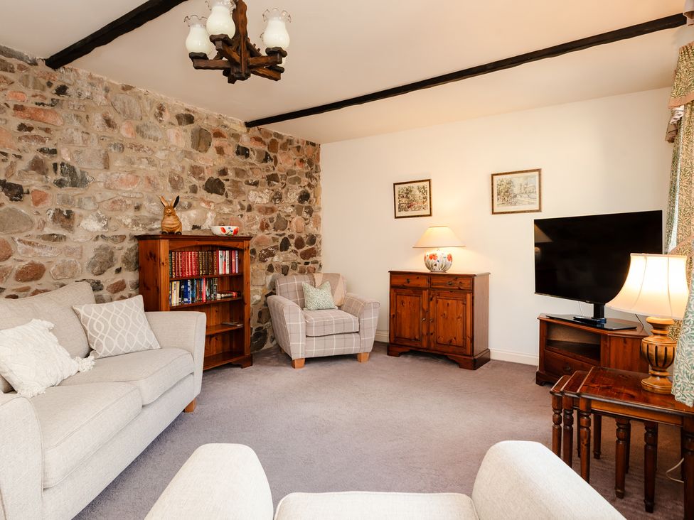 A living room with a sofa and TV at Bramble Cottage in Akeld near Wooler