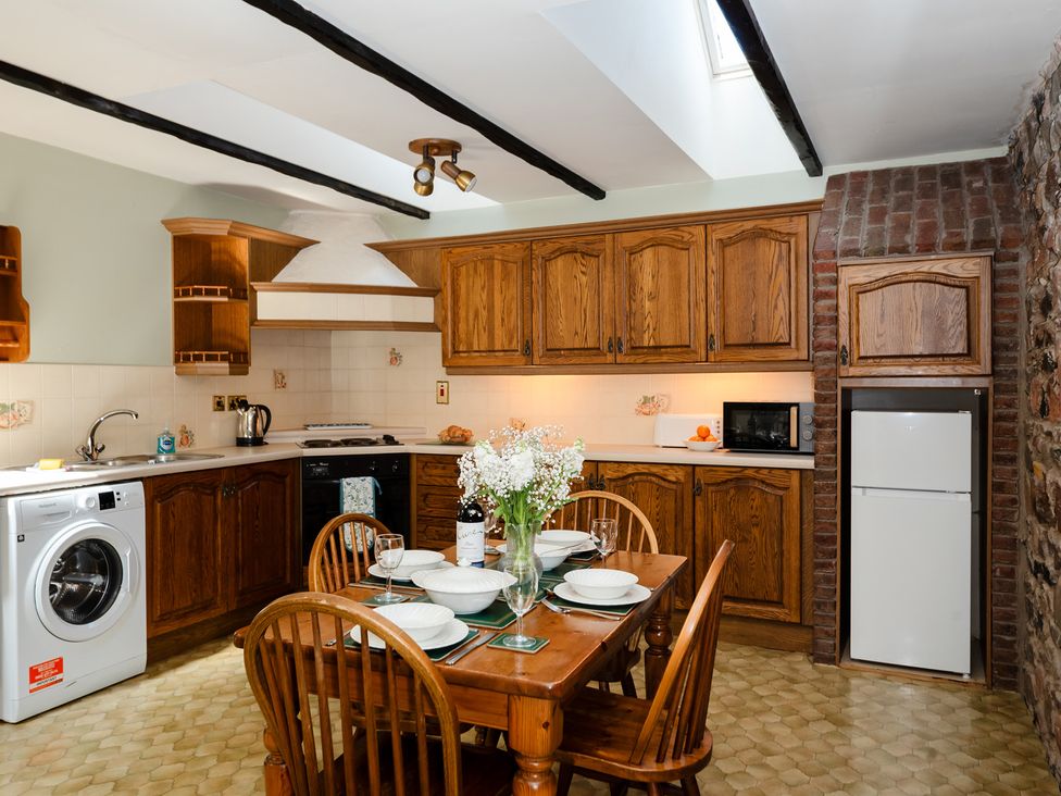 A kitchen with cabinets and a dining table at Bramble Cottage Akeld near Wooler