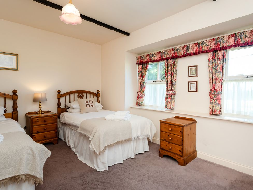 A bedroom with two beds and a nightstand at Bramble Cottage near Akeld near Wooler