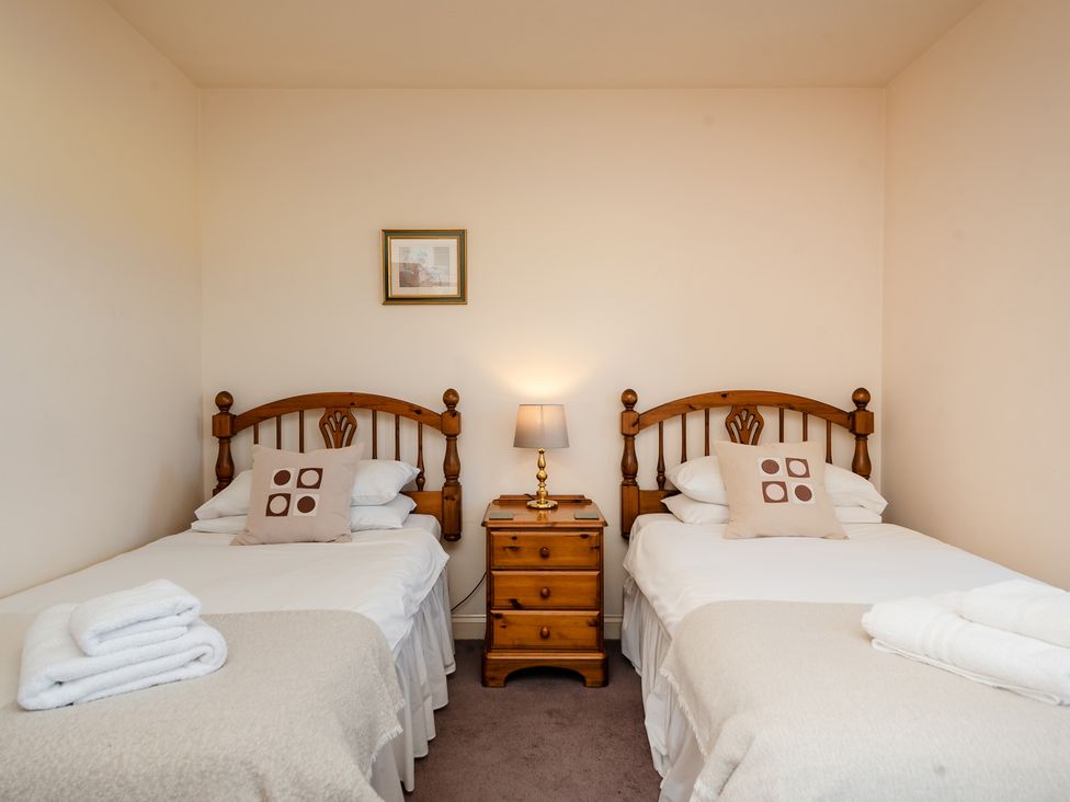 A bedroom with two beds and a nightstand at Bramble Cottage in Akeld near Wooler