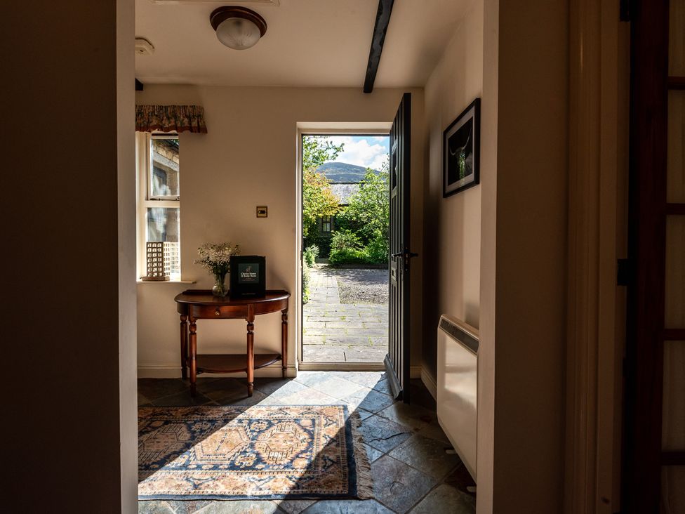 A hallway with a table and flowers at Bramble Cottage Akeld near Wooler