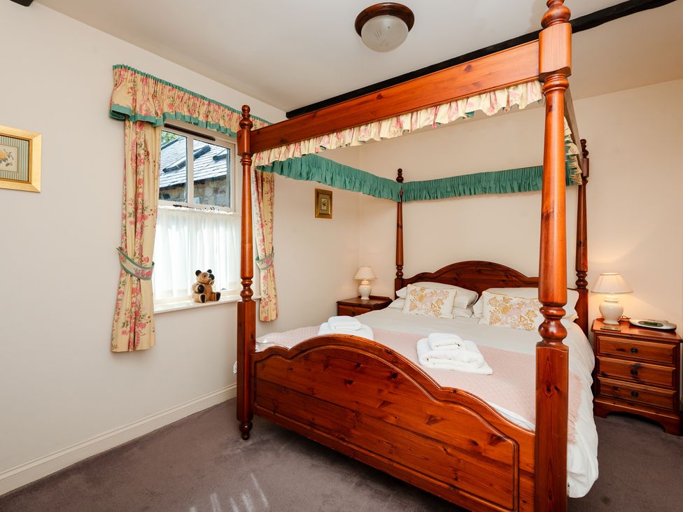 A bedroom with a four-poster bed and a bedside table at Bramble Cottage Akeld near Wooler