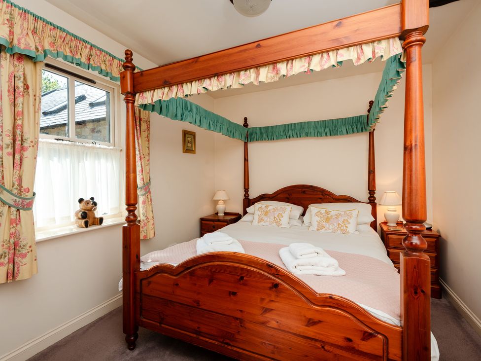 A bedroom with a four-poster bed and window at Bramble Cottage Akeld near Wooler