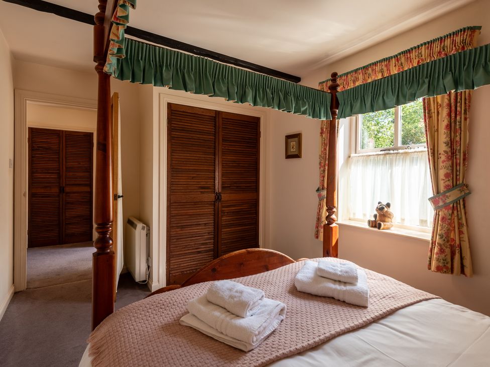 A bedroom with a four-poster bed and towels on the bed at Bramble Cottage Akeld near Wooler
