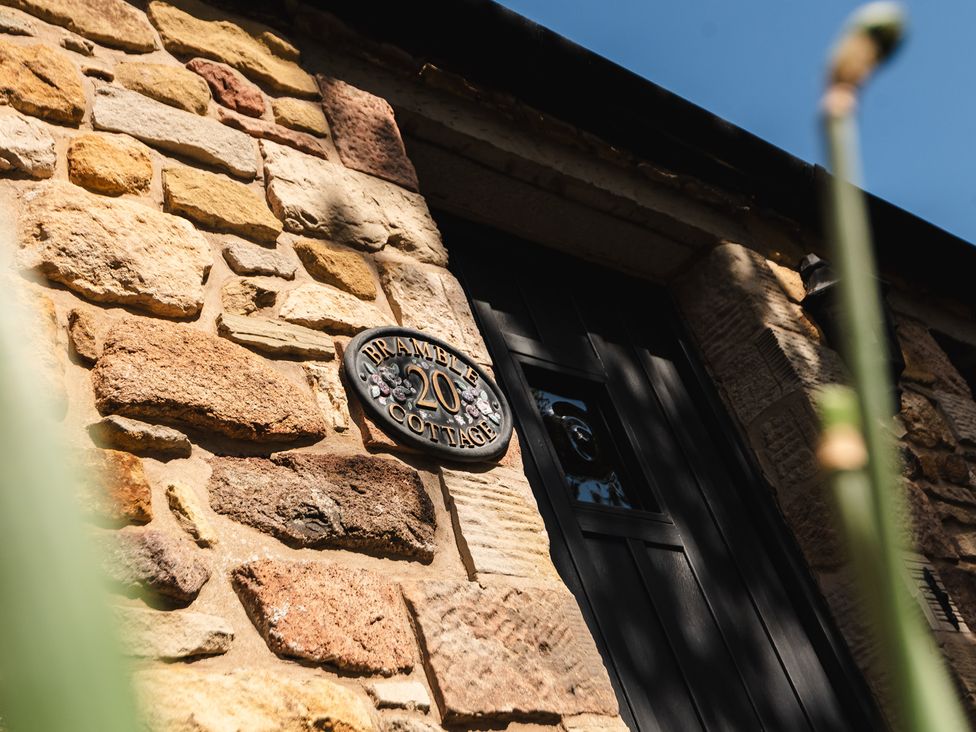 A stone wall with a door and a sign at Bramble Cottage Akeld near Wooler