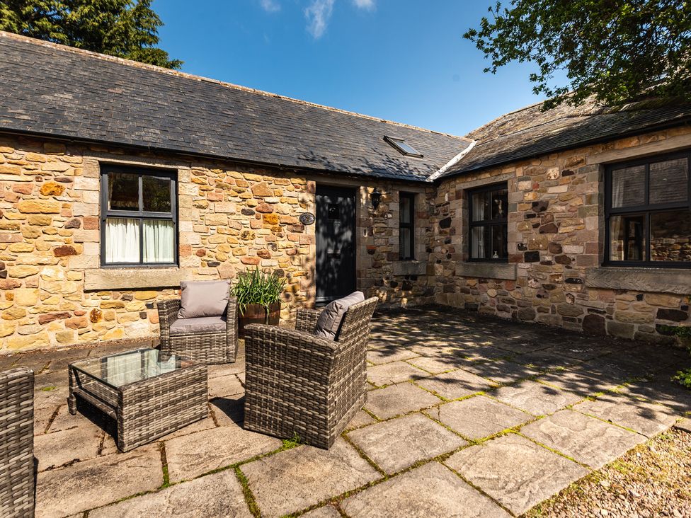 An outdoor seating area with a stone wall at Bramble Cottage in Akeld near Wooler