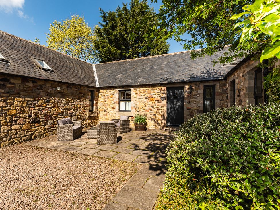 An outdoor seating area with stone walls and patio at Bramble Cottage in Akeld near Wooler