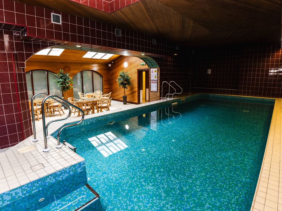 An indoor pool area with seating and plants at Tile Rouge in Wooler