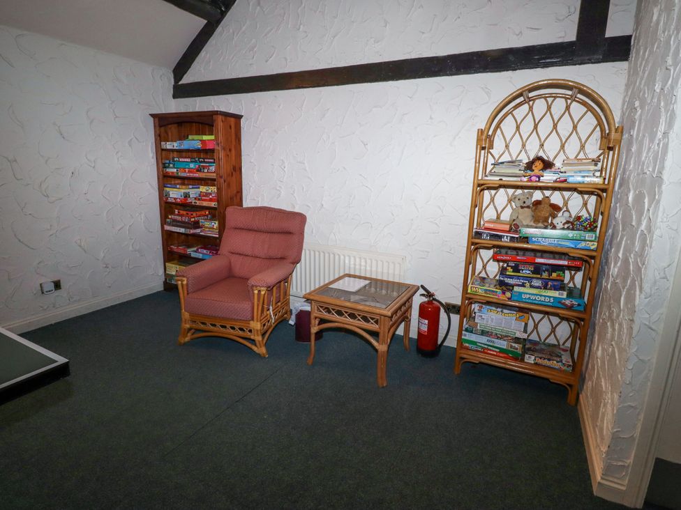 A snug with a chair, tables, and bookcases at Hollyhock in Akeld near Wooler