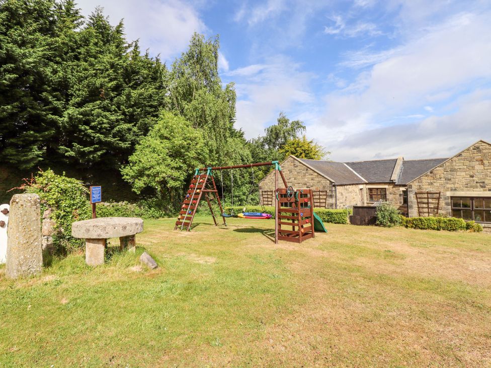 A garden with a swing set and stone mill at Hollyhock in Akeld near Wooler