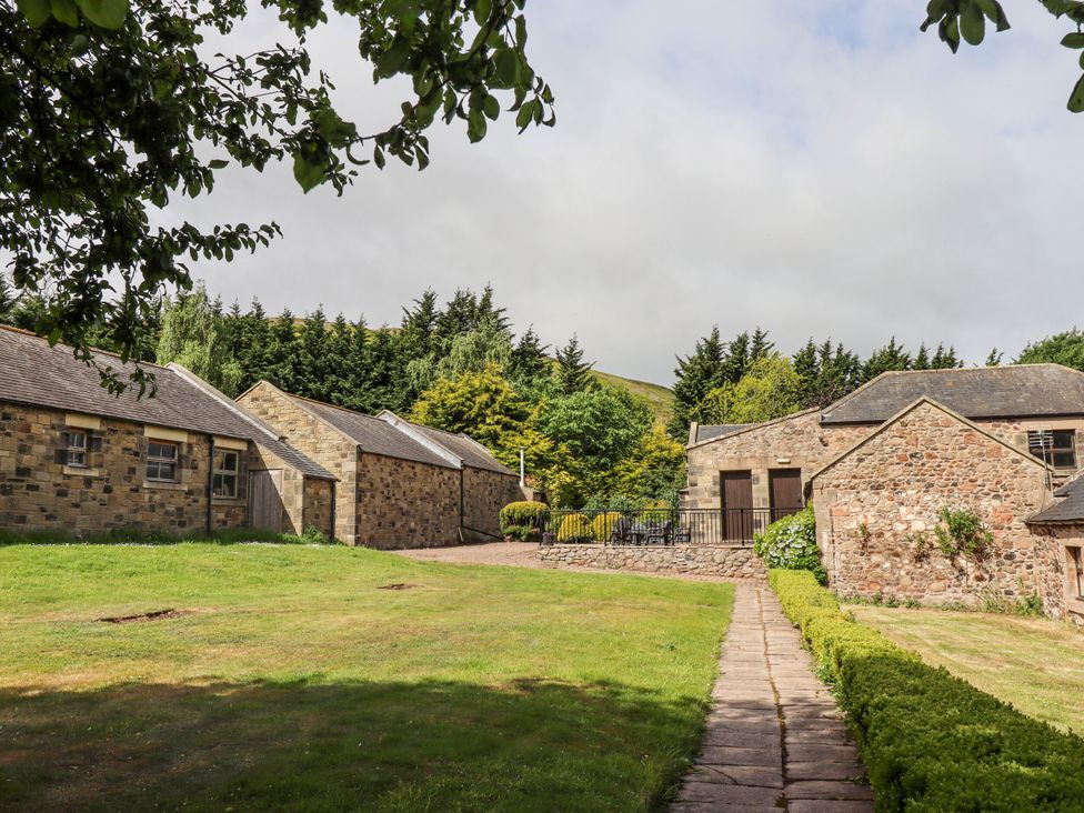 An outdoor area with stone buildings and a pathway at Hollyhock in Akeld near Wooler