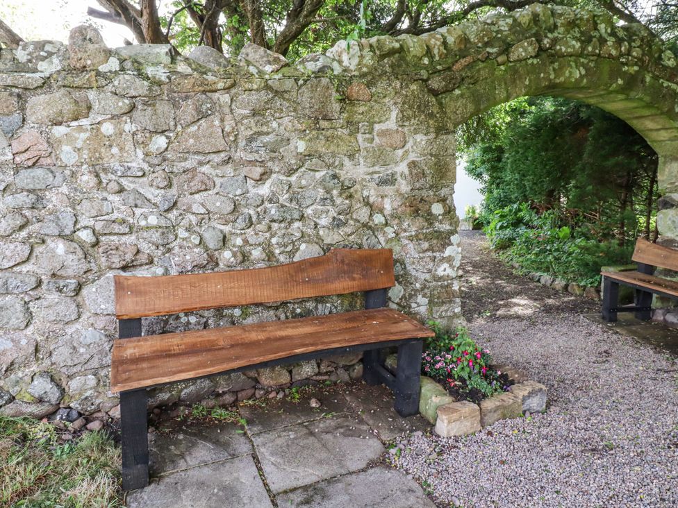 A garden with a stone wall and wooden benches at Hollyhock in Akeld near Wooler