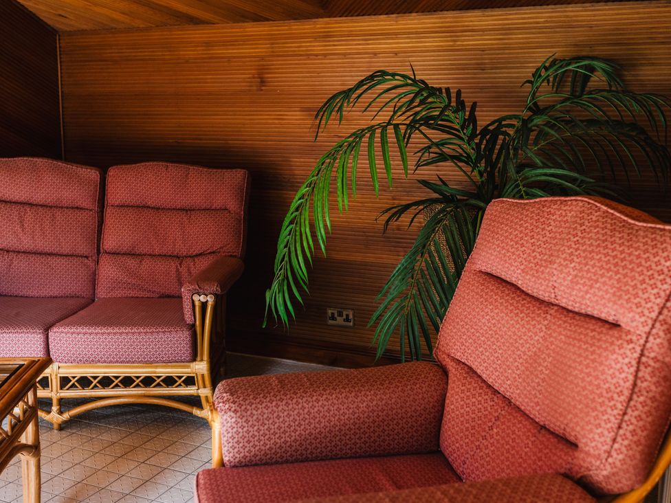 A living room with a sofa, armchair, and plant at Pansy Plot in Akeld near Wooler