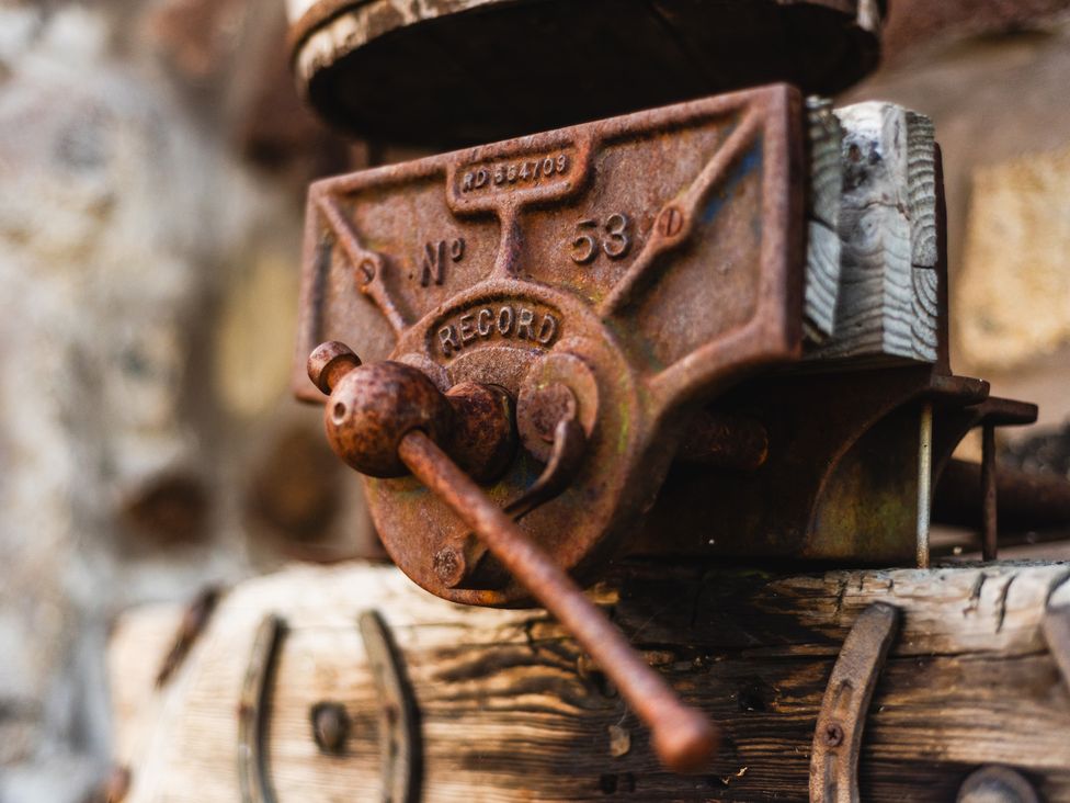 A close-up of a rusty mechanism with a handle on a wooden surface at Pansy Plot in Akeld near Wooler