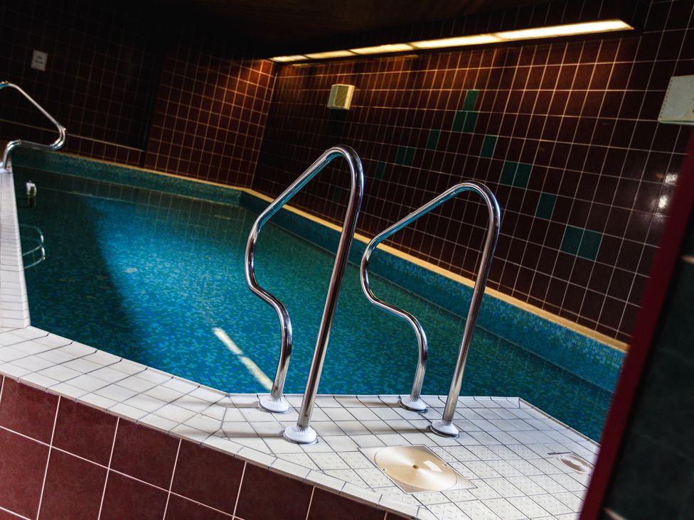 An indoor pool with tiled walls and metallic railings at Heatherview in Wooler