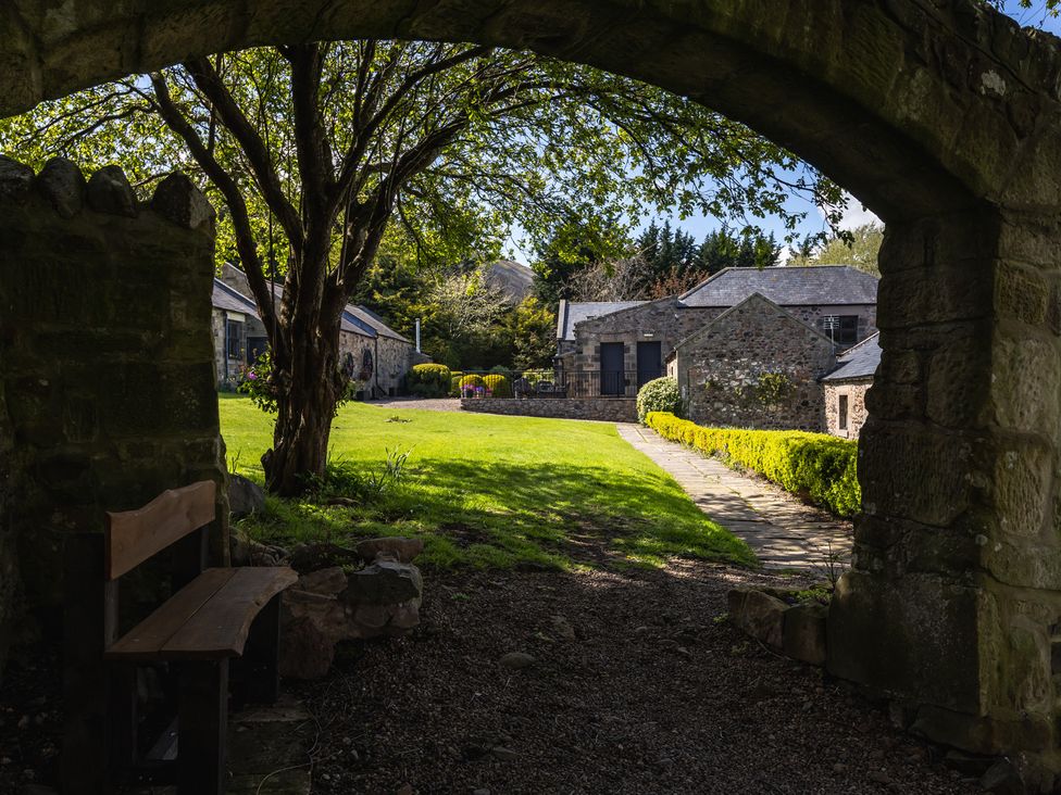 A garden with a stone archway and buildings at Heatherview in Wooler